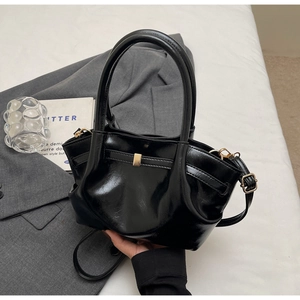Dettaglio della borsa tote nera lucida con fibbia dorata e tracolla sottile
