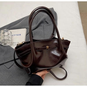 Dettaglio borsa tote in pelle marrone scuro lucida con dettagli in metallo oro