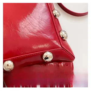 Detail of red oil wax leather handbag featuring silver studs and stylish fringe tassels