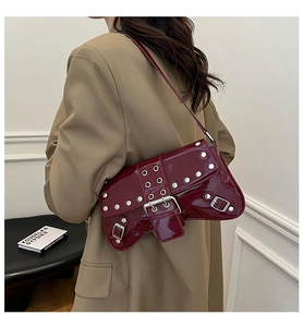 Detail of burgundy patent leather underarm bag with silver studs and punk metal buckles