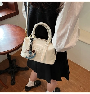 Détail du sac Boston blanc brillant avec logo embossé et pendentif cheval en bois