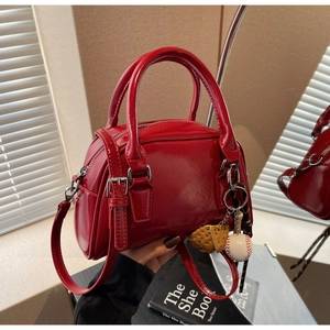 Detail of red patent leather bowling bag with round handles and athletic charms