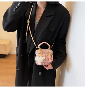 Detail of pink tweed bucket bag with gold chain strap and plush doll charm on black blazer