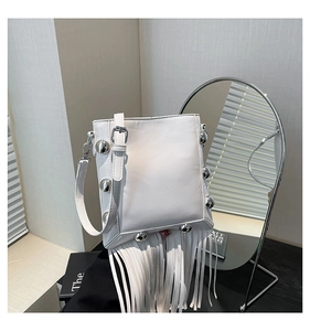 Detail of white PU crossbody bag with silver metal studs and long fringe decorative tassels