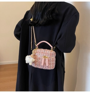 Close-up of pink tweed box bag with gold chain strap and cute white plush charm