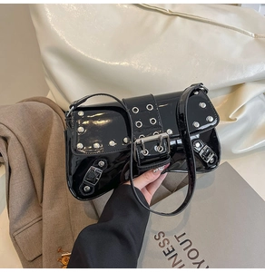 Close-up of black patent leather underarm bag with silver rivets and punk Y2K metallic studs