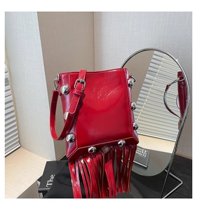 Detail of red tassel bucket bag featuring glossy leather and silver sphere studs