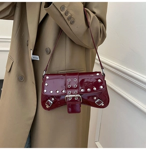 Detail of burgundy patent leather shoulder bag featuring silver rivets and metal buckles