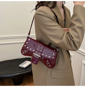 Detail of burgundy patent leather underarm bag with silver rivets and studs
