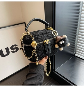 Detail of black tweed quilted box bag with chain strap and fuzzy charcoal charm