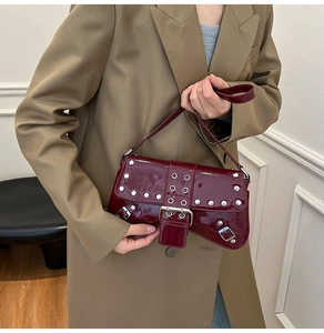 Detalle del bolso baguette de charol burdeos con tachuelas plateadas en una modelo real