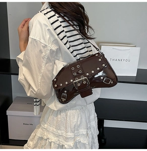 Detail of dark brown patent leather shoulder bag with silver studs and buckle strap
