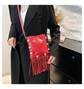 Detail of red patent leather bucket bag with long fringe and silver rivet accents