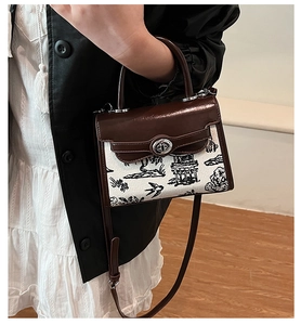 Detail of white Kelly bag with black landscape print and brown leather handle