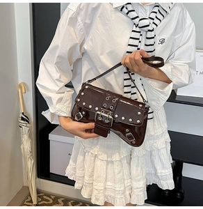 Detalle del bolso de charol marrón oscuro con remaches plateados y correas con hebilla