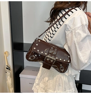 Detail of dark brown patent leather shoulder bag with silver rivets and metal buckle