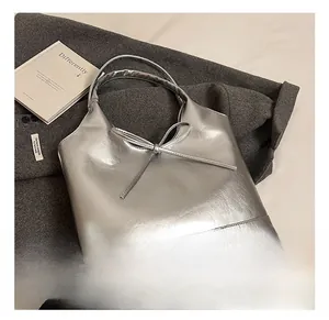 Detail shot of silver faux leather tote bag with metallic finish and bow accent