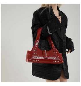 Detail van rode olie-was lederen schoudertas met zilveren klinknagels op blazer