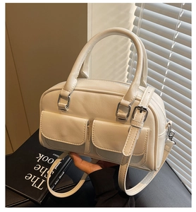 Close-up of cream oil-wax leather Boston bag with silver buckles and dual pockets