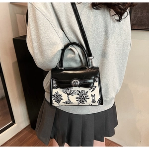 Detailed view of mini crossbody bag with black handle and white nature print on model