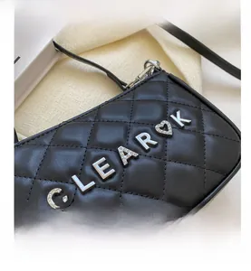 Detailed macro view of black quilted leather texture with silver heart logo hardware