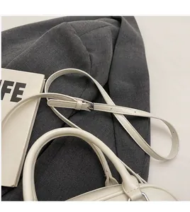 Detail of adjustable silver buckle and smooth cream leather strap on Boston bag