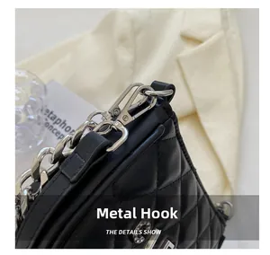 Close-up of the silver metal chain and hooks on the black quilted crossbody bag