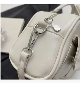 Close-up of premium silver hardware and subtle oil wax leather texture on a white bag