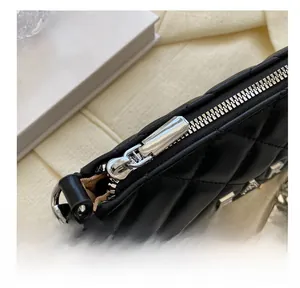 Close-up of smooth silver metal zipper and chain on black quilted leather handbag