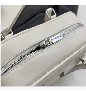 Macro detail of silver metal zipper and smooth stitching on off-white leather bag