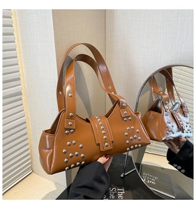 Detailopname van de karamel lederen tote bag met zilveren studs en vintage rocker stijl