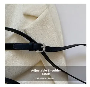 Detail of adjustable black leather shoulder strap with a silver buckle on tweed fabric