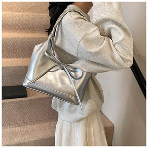 Silver metallic leather shoulder bag with a large bow detail shown on a model