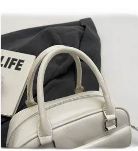 Detail of white glossy oil wax leather Boston bag with round handles and silver zipper