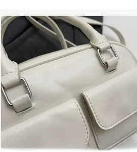 Close-up of cream white oil wax leather Boston bag with silver hardware and pockets