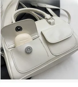 Detail of off-white faux leather Boston bag showing functional front pocket for earbuds