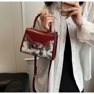 Detail showing the two-tone red leather and patterned fabric texture of the handbag