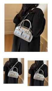 Detailed view of silver metallic Boston bag with dual front flap pockets and leather finish