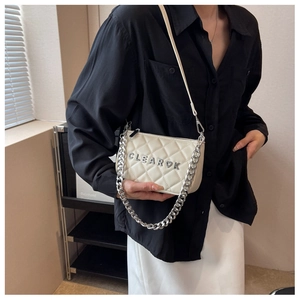 Detail of white quilted crossbody bag with metal letters and elegant silver chain strap