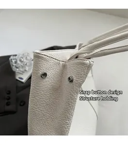 Detailansicht der seitlichen Druckknöpfe an einer weißen Ledertasche zur Formfixierung