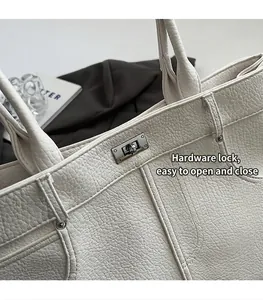 Detail der weißen Lychee-Ledertextur und Metall-Drehverschluss an der Modetragetasche