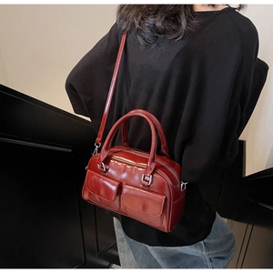 Close-up of wine red wax leather Boston bag featuring dual front pockets and silver hardware