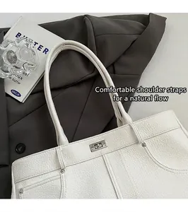 Detail der weißen Handtasche mit Litschi-Muster, silbernem Drehverschluss und zwei dünnen Riemen