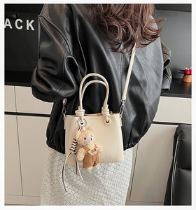 Creamy white lychee texture tote bag with a cute bear charm worn with a black leather jacket