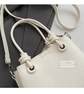 Close-up of white lychee pattern leather handbag with knotted handle and soft texture