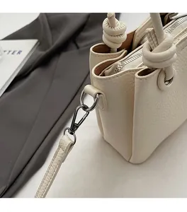 Close-up of lychee textured cream leather handbag with silver hardware and knotted strap