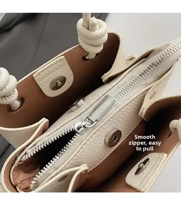 Detailed macro of smooth silver zipper and magnetic clasp on cream textured leather bag