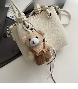 Detail of lychee textured cream leather tote bag featuring a cute teddy bear charm