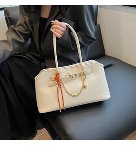 Detail of white PU leather bag with golden chain and orange woven cord on handle