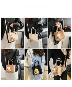 Detail view of multi-compartment commuter bag in three colors with cute bear charm